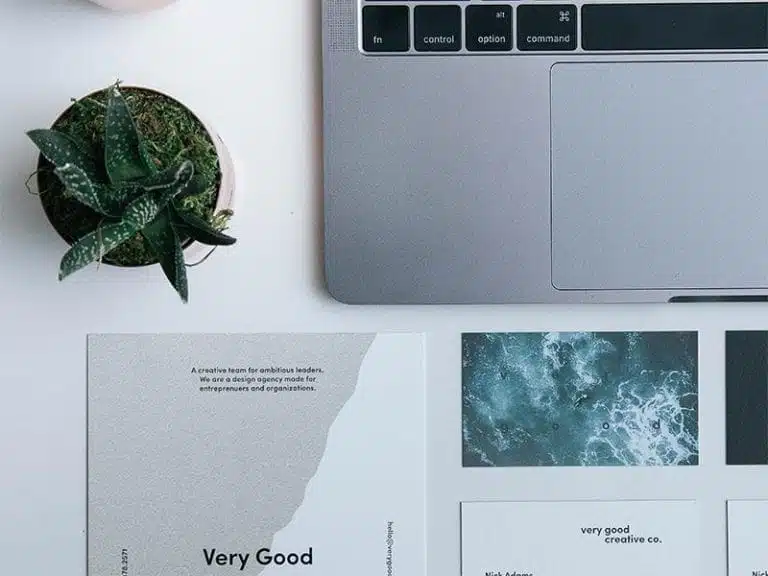 stol snimljen iz ptičje perspektive na njemu blok za pisanje, laptop, i lijepa biljka (cvijet)